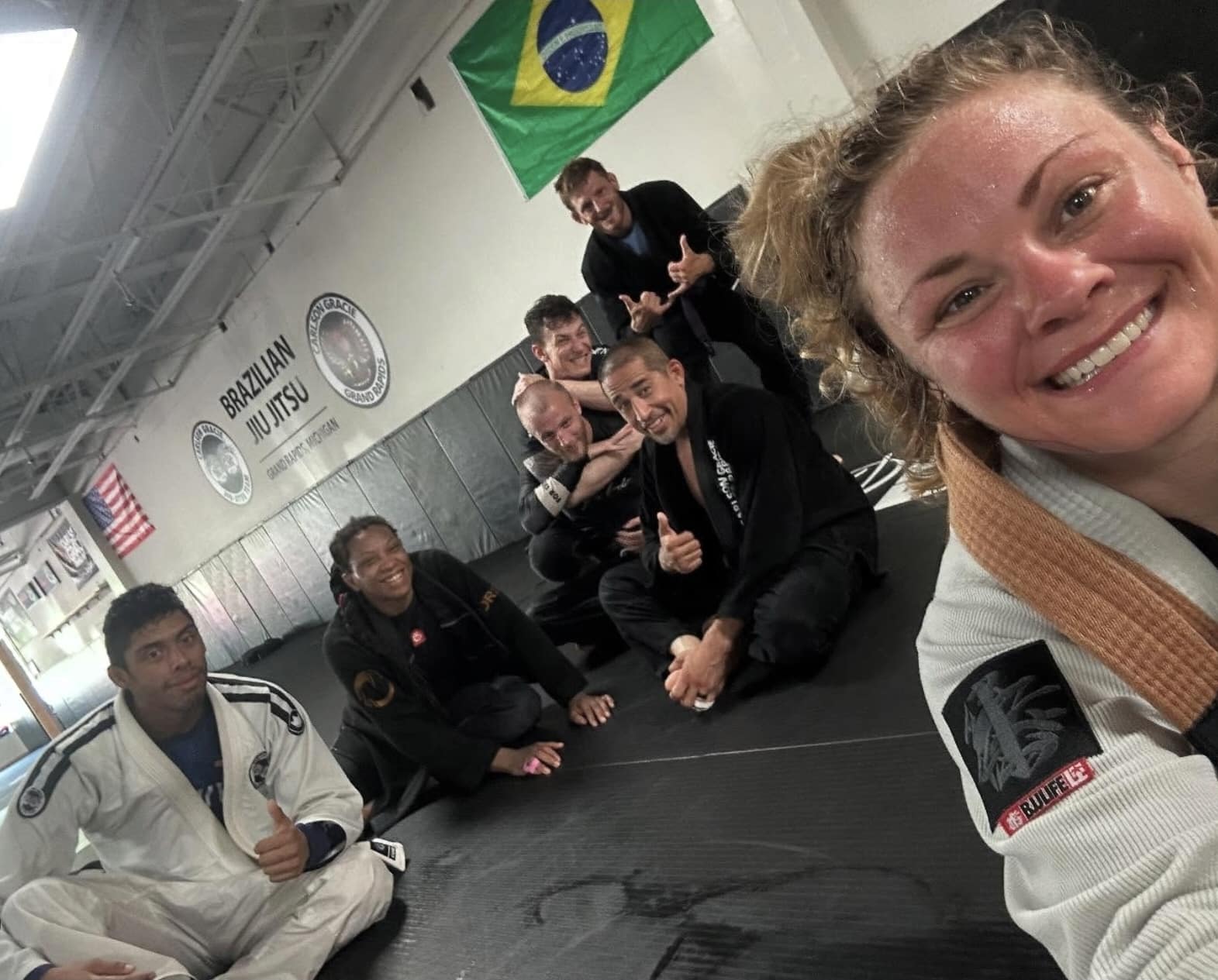 Carlson Gracie Grand Rapids BJJ students smiling wearing gi uniforms after BJJ training class.