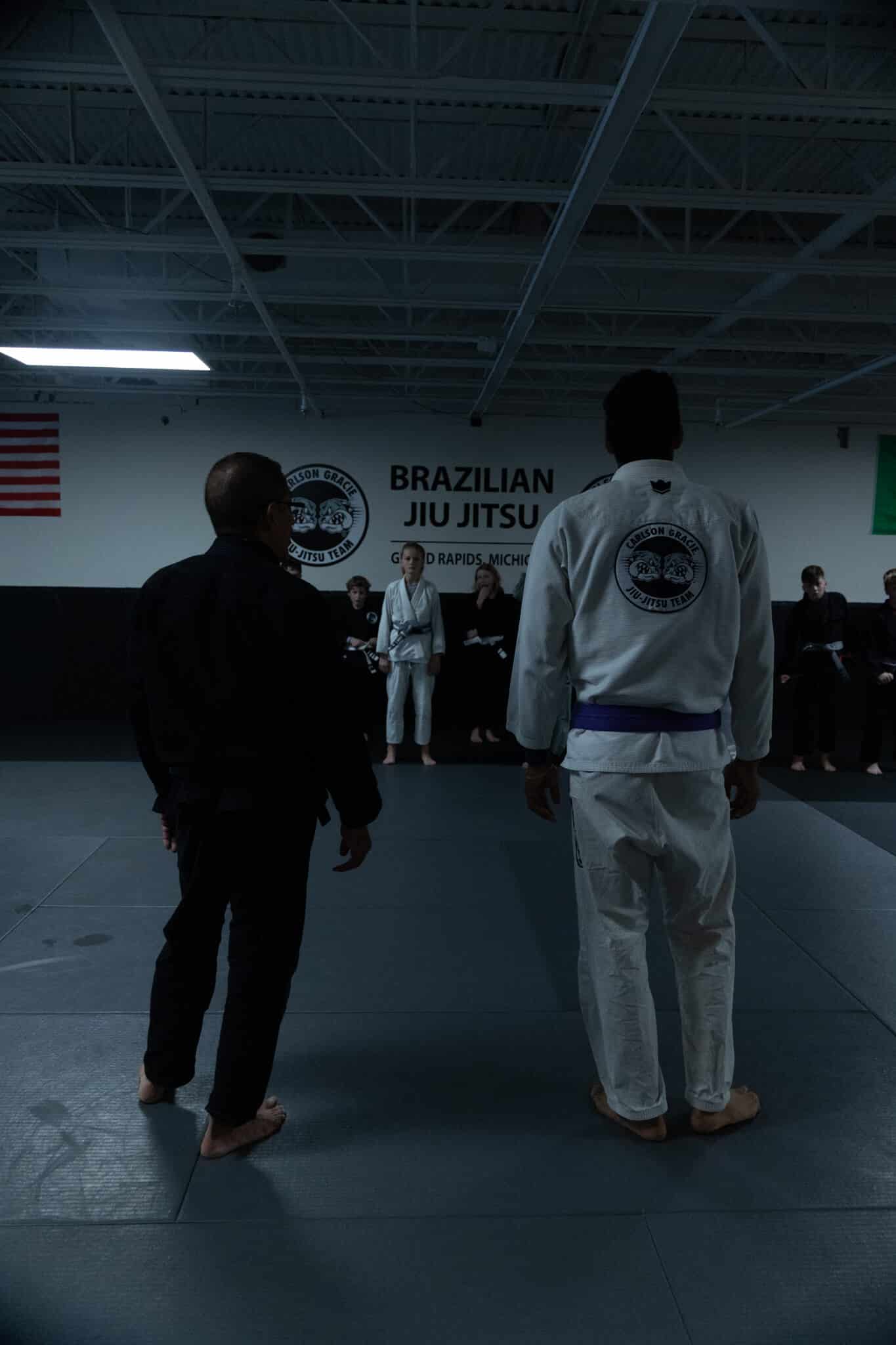 Carlson Gracie Grand Rapids instructors standing in front of students wearing gi uniforms during BJJ class.